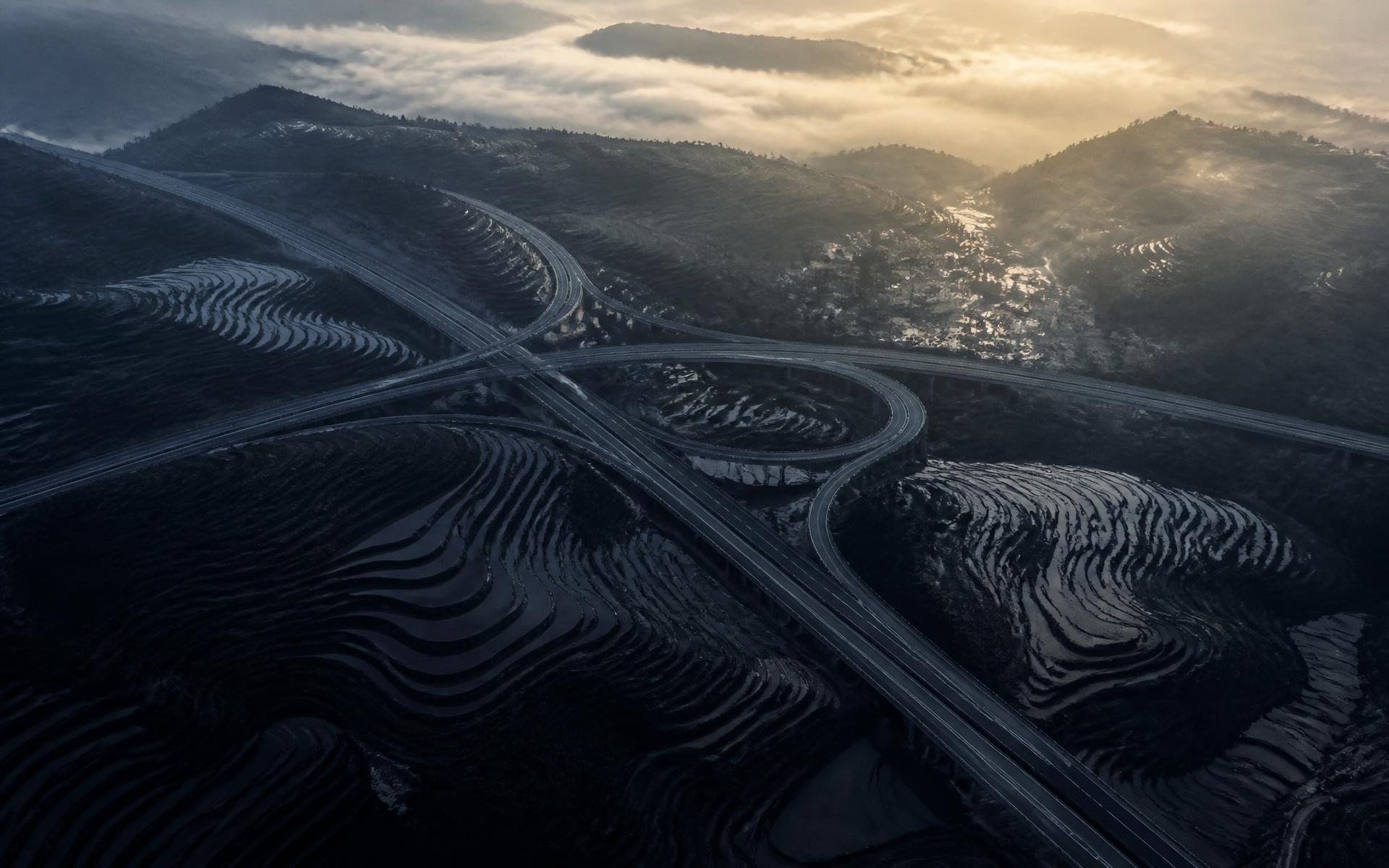 Aerial view of terraced farmland intersected by clean infrastructure lines at dawn