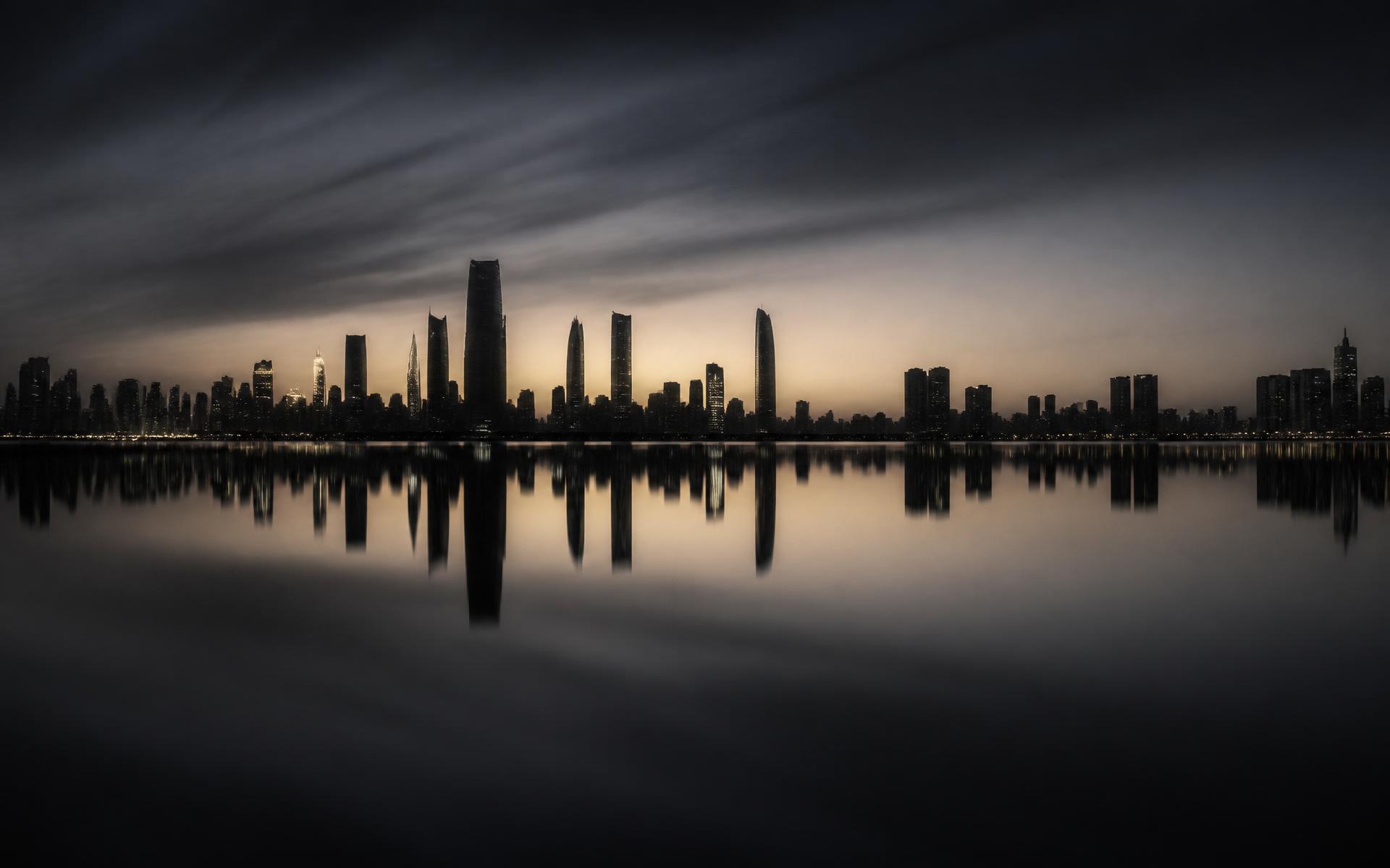 Distant skyline reflected in still water before sunrise