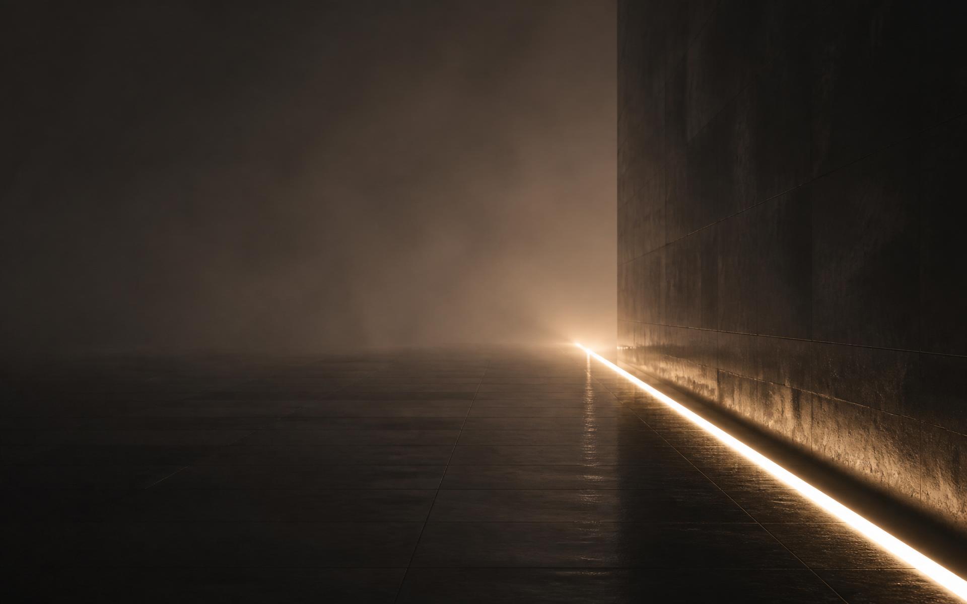 A single line of warm light receding into fog along a dark polished wall
